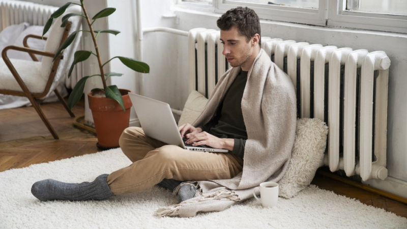 Мужчина с ноутбуков возле батареи с отключенным отоплением в Москве